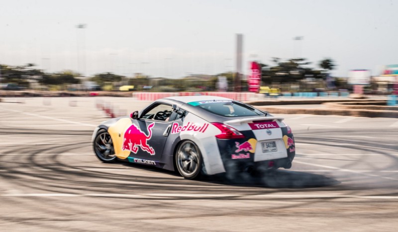 Sports car sponsored by Red Bull in a drift competition with multiple tire marks on concrete